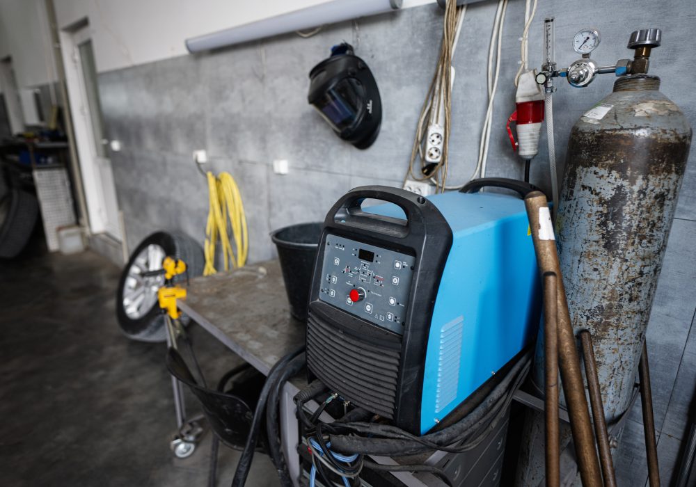 A detailed view of an industrial workshop featuring welding equipment, gas cylinder, and various tools. Ideal for depicting a professional work environment in a manufacturing setting.